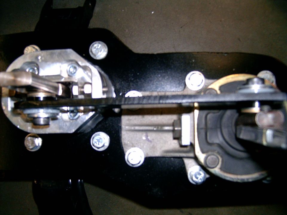 Close-up of vehicle mechanical assembly with metal parts and black plate.