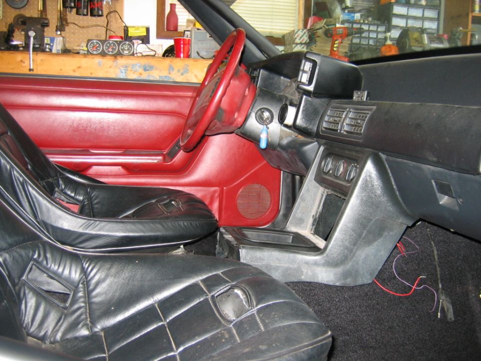 Interior of a 1992 Ford Mustang with black racing seats and red dashboard.