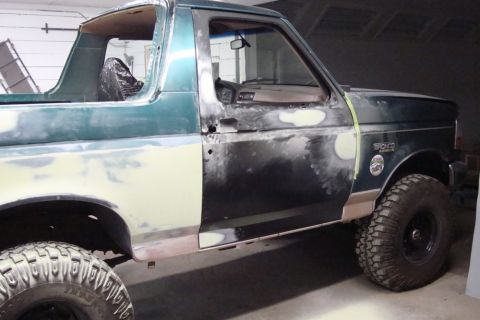 1996 Ford Bronco - Photograph of a teal Ford Bronco's side during a paint restoration, not a technical document.