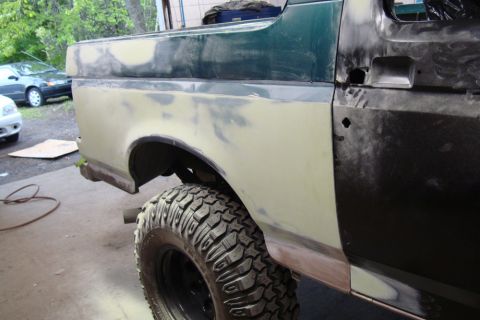 1996 Ford Bronco - Photograph of a Bronco rear quarter in primer outdoors during paint prep, not a technical document.