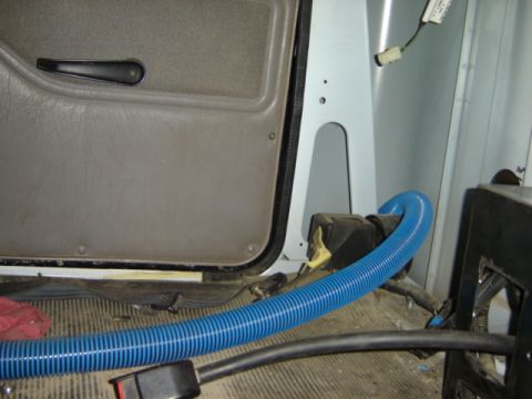 1992 Ford Bronco - Photograph of a cab interior door panel and floor with a hose, not a technical document.