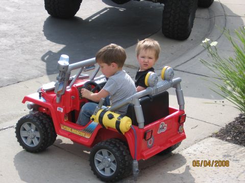 1994 Ford Bronco - Children play in a red toy fire rescue jeep, with a large tire of another vehicle in the background.