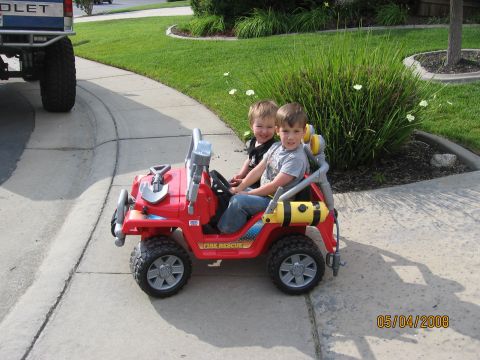 1994 Ford Bronco - Kids enjoy a ride in a toy fire rescue vehicle on a sunny day, with a pickup truck nearby.