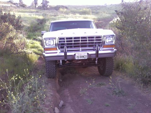 1978 Ford Bronco - This 1978 Ford Bronco is shown driving off-road on a dirt path with vegetation on either side.