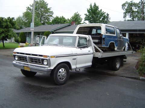 1979 Ford Bronco - Tow truck transports a disassembled Ford Bronco, likely for restoration or parts.