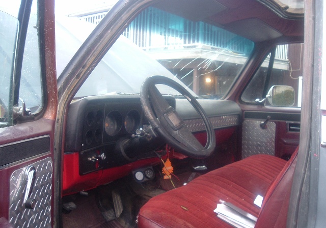 Red velour bench seat and diamond plate door panels in a maroon truck interior with a cracked windshield