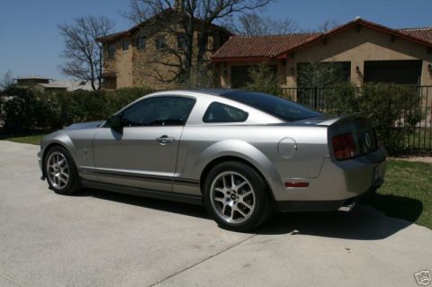 2008 Ford Mustang - Silver 2008 Ford Mustang coupe with racing stripes and a rear spoiler.