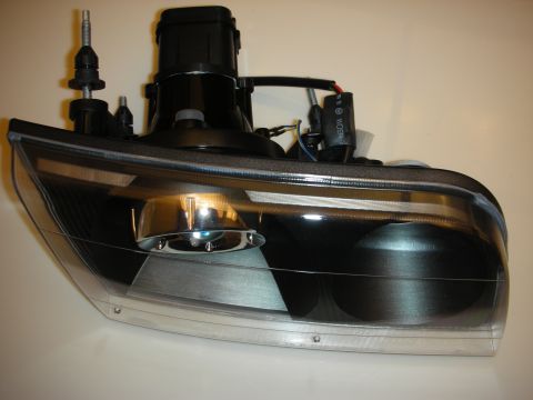 1998 Ford Crown Victoria - Rear view of an aftermarket black-housing projector headlight assembly showing wiring and adjusters.