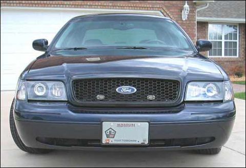 1998 Ford Crown Victoria - Head-on view of a dark blue Ford sedan showing the grille emblem and dual projector headlights.