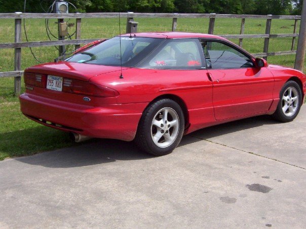 Red 1993 Ford Probe coupe parked on concrete, rear 3/4 view