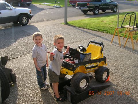 1996 Ford Bronco - Two children interact with a toy vehicle in a driveway, with other real vehicles visible in the background.