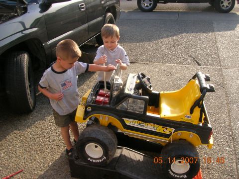 1996 Ford Bronco - Two young boys tinker with a yellow and black toy truck, with a real truck in the background.
