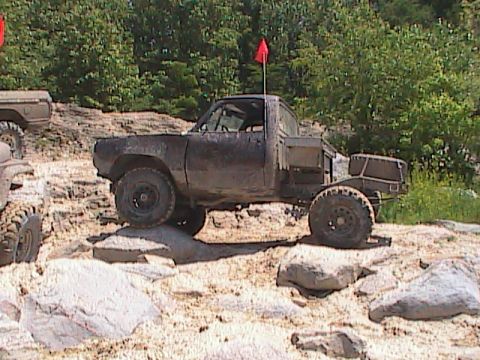 1980 Dodge Magnum - This pickup truck, likely from the early 1970s, is shown off-roading over rocks with another vehicle partially visible.