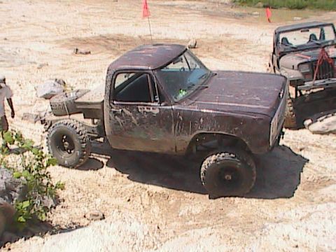 1980 Dodge Magnum - This lifted pickup truck navigates a sandy off-road course, with another vehicle visible in the background.