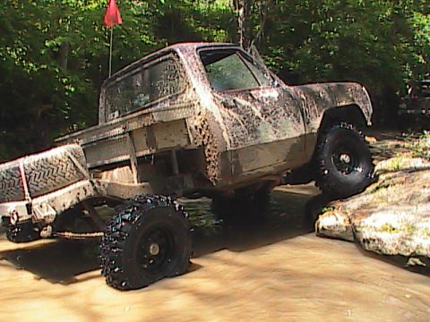 1980 Dodge Magnum - A heavily modified pickup truck navigates a challenging off-road course with a red flag visible in the background.