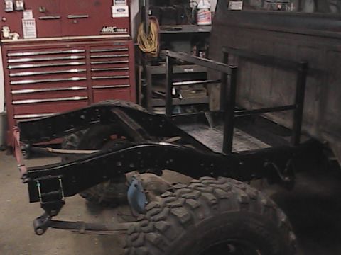 1980 Dodge Magnum - The chassis of a truck, large off-road tires and a custom-built rack, is shown in a workshop setting.