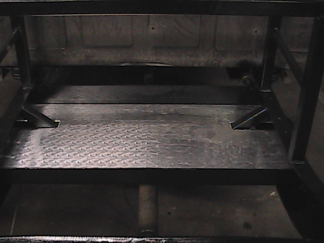 Truck bed interior with diamond plate flooring and black metal frame structure. Supermotors.net logo visible