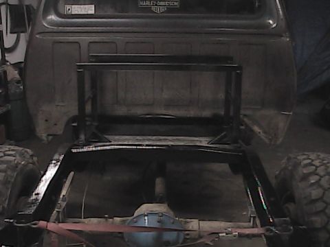 1980 Dodge Magnum - This image shows the rear chassis of a truck, modified with a custom-built metal rack. The vehicle's large tires are prominent.