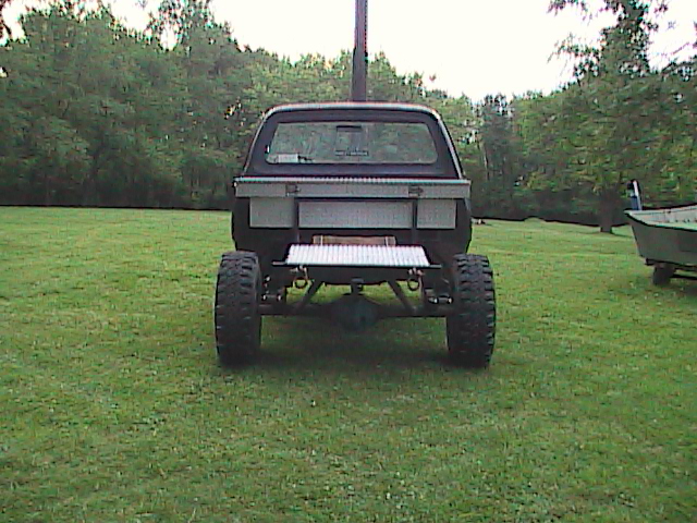Rear view of a lifted pickup truck with large off-road tires and a toolbox mounted in the bed
