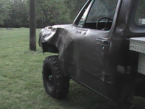 1980 Dodge Magnum - This pickup truck has significant damage to its front fender and door, with large off-road tires visible.