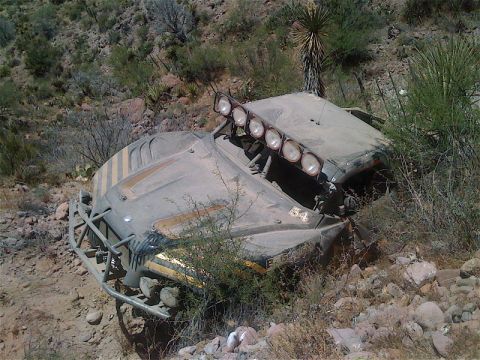 2008 Ford Bronco - Off-road buggy crashed on a rocky desert hillside, with multiple lights mounted on the roof.