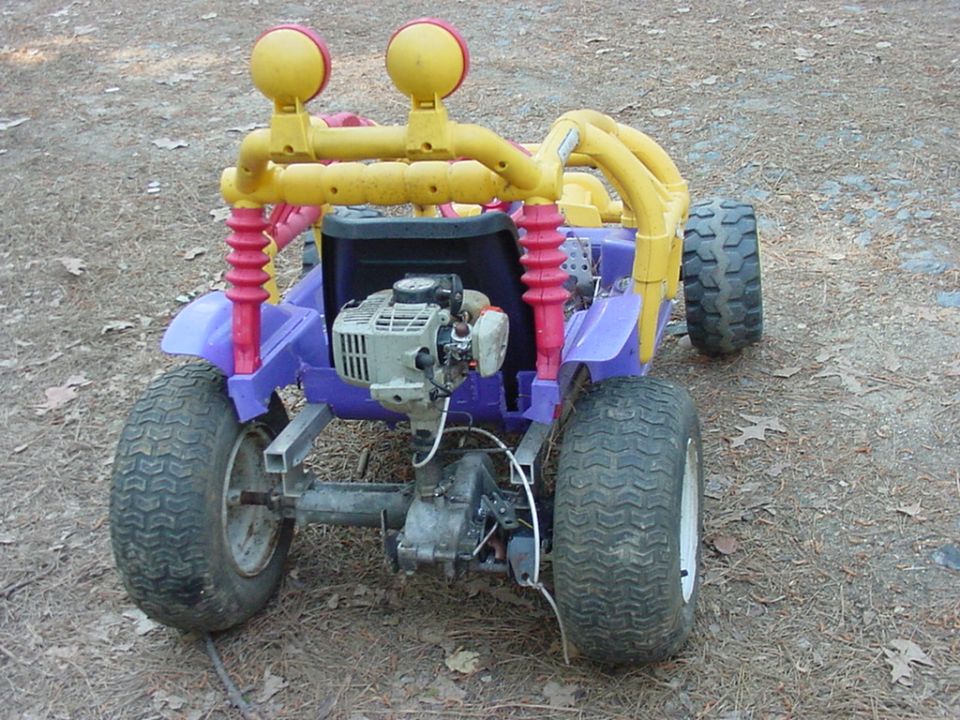 Custom go-kart with purple body, yellow roll cage, dual headlights, and exposed engine
