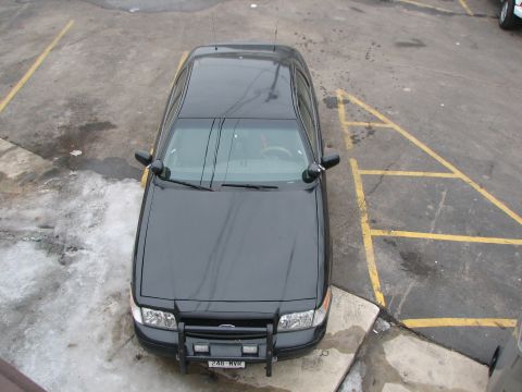 2000 Ford Crown Victoria - A black police car, likely a 2000 Ford Crown Victoria, is parked in a lot, viewed from directly overhead.
