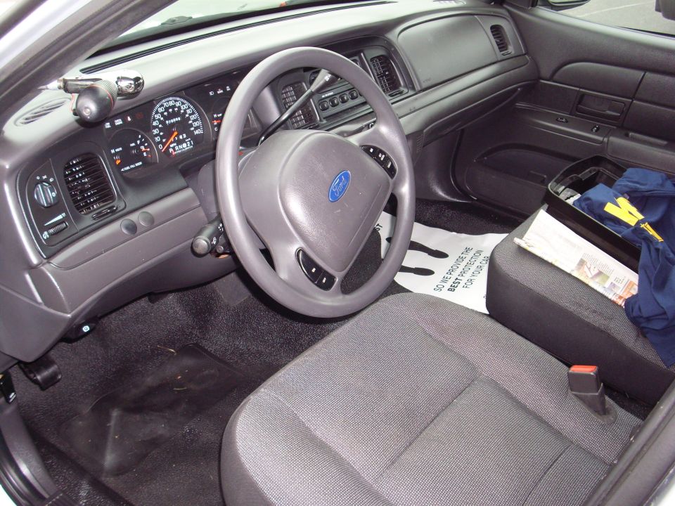 Interior of a 2004 Ford Crown Victoria police car, showing dashboard, steering wheel, and seats
