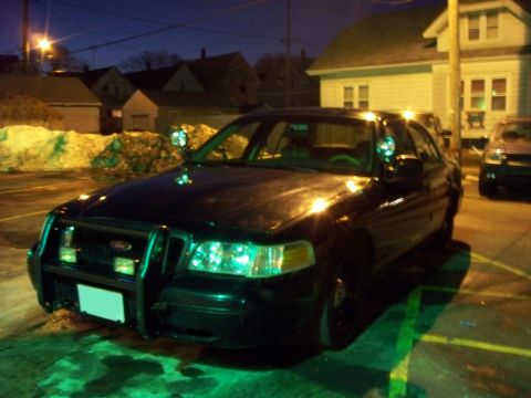 2000 Ford Crown Victoria - A black 2000 Ford Crown Victoria police car is parked at night, illuminated by streetlights and its own headlights.