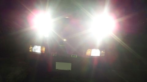 2000 Ford Crown Victoria - The bright headlights of a dark vehicle obscure much of its front details.