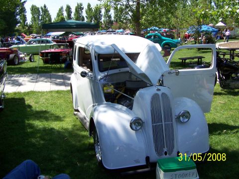 1972 Ford Ranchero - A white sedan is displayed with its hood and door open at an outdoor car show.