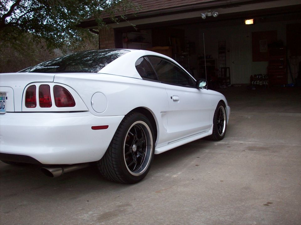 White 1997 Ford Mustang coupe, rear 3/4 view, black rims