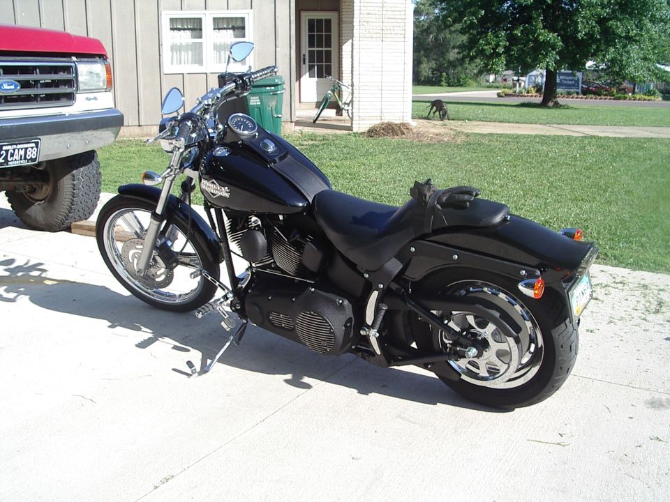 Black Harley-Davidson motorcycle parked on a driveway next to a red Ford truck
