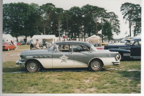1991 Ford Crown Victoria - A vintage police car is parked on a grassy field with tents and trees in the background.