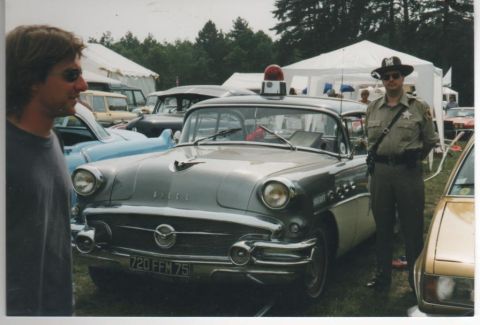 1991 Ford Crown Victoria - A 1956 Buick Century, possibly a police car, is shown with a sheriff standing beside it.