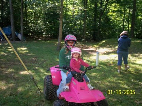 1997 Dodge 1500 - Two young girls enjoy a ride on a pink ATV in a grassy, wooded area on a sunny day.