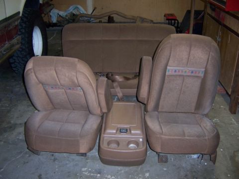 1991 Ford Bronco - Interior car seats and console removed from a vehicle, showing brown fabric and a central console unit.