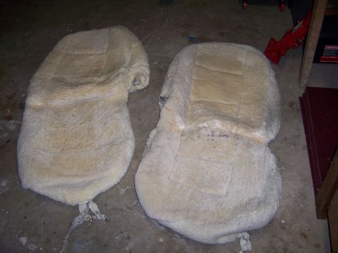 1991 Ford Bronco - Two sheepskin seat covers are shown on a garage floor, possibly for restoration or cleaning.