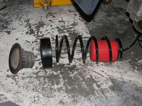 2002 Toyota Sequoia - Suspension components laid out on a garage floor, including a coil spring and bump stop.