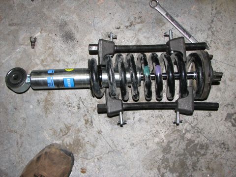 2002 Toyota Sequoia - A vehicle's shock absorber assembly is shown with a spring compressor tool engaged on the coil spring.