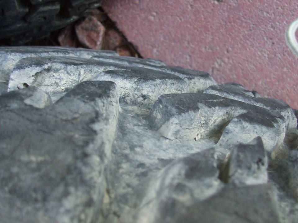 Close-up of a knobby off-road tire tread with dirt and debris