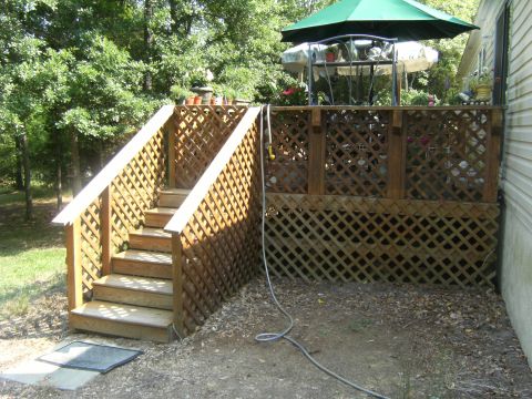 1992 Ford F-150 - A wooden deck with lattice skirting and stairs leads to an outdoor seating area under a green umbrella.