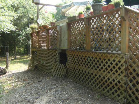 1992 Ford F-150 - A weathered wooden deck with diamond-pattern lattice skirts the lower portion, while potted plants adorn the upper railing.