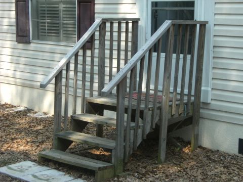1992 Ford F-150 - Exterior view of a weathered wooden staircase with railings, set against the side of a house.