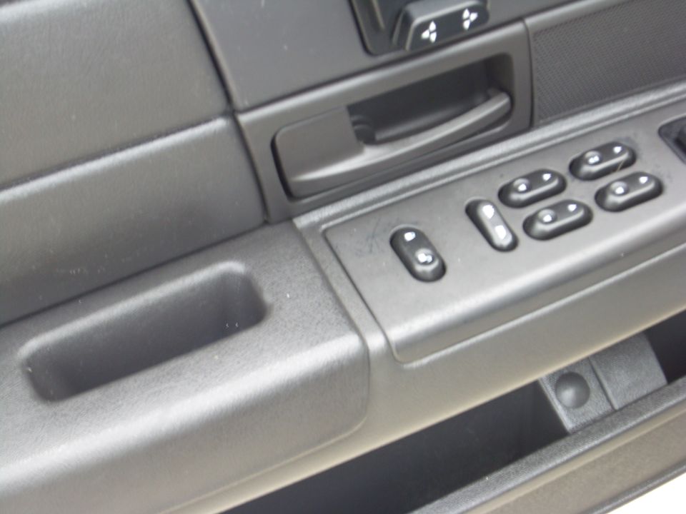Interior door panel with power window controls and a storage cubby