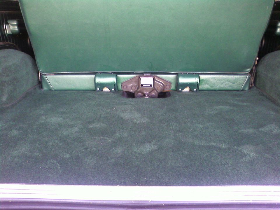 Green carpeted cargo area with folded seat and latch mechanism