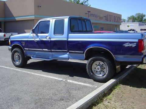 1996 Ford F-250 - This two-tone blue Ford F-250 truck is parked in a lot, showing its side profile.