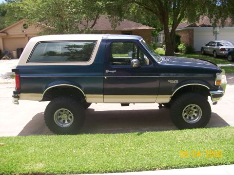 1992 Ford Bronco - This 1992 Ford Bronco is parked on a residential street, showing its two-tone paint and lifted stance.