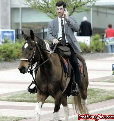 2000 Mercury Grand Marquis - A man in a suit rides a horse while talking on a cell phone, with other people in the background.