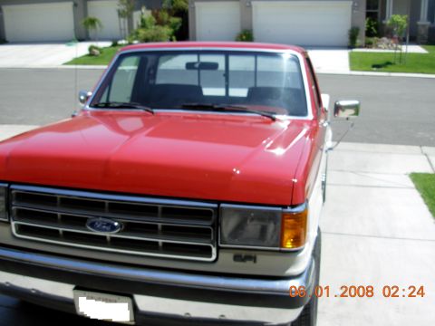 1988 Ford F-150 - This red and white Ford F-150 truck is seen from the front, parked in a driveway.